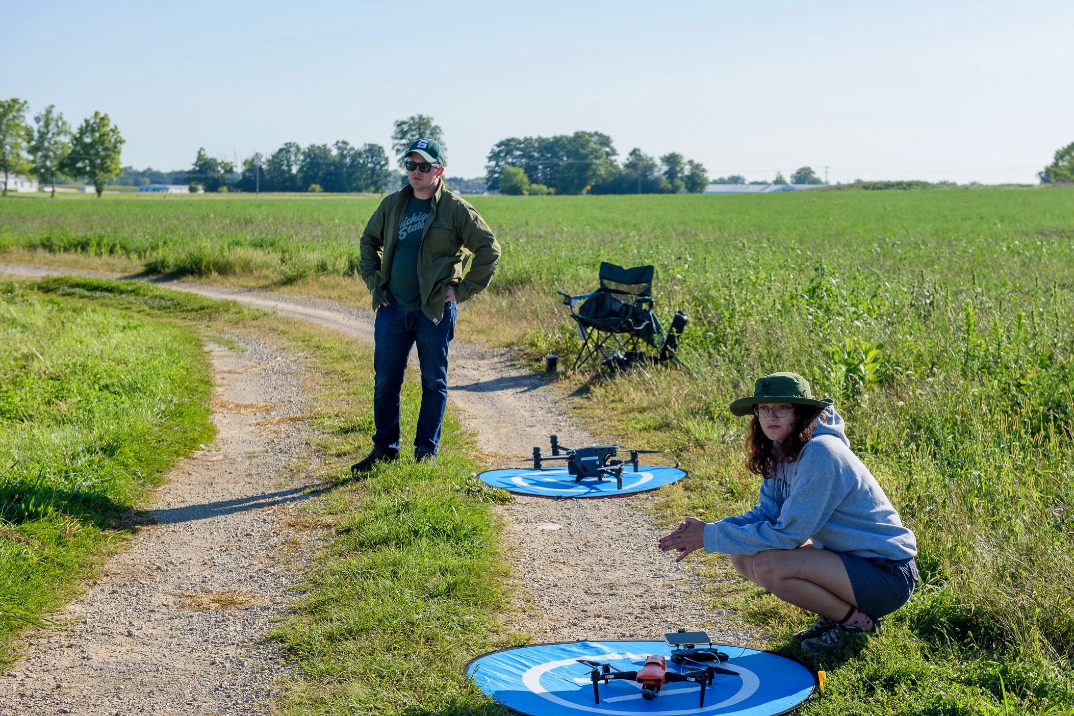 Two analysts waiting in a field with two drones