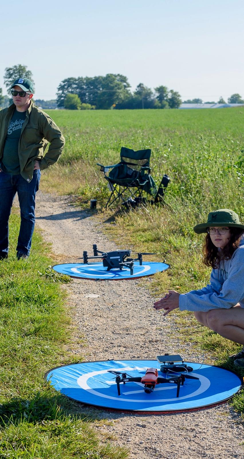 Two analysts waiting in a field with two drones