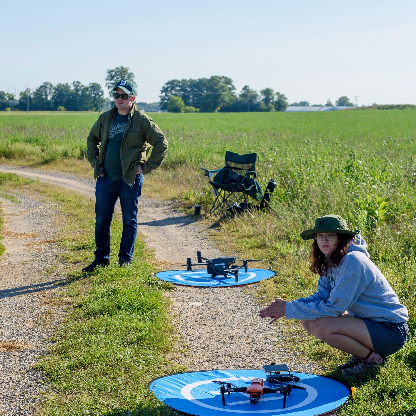 Two analysts waiting in a field with two drones